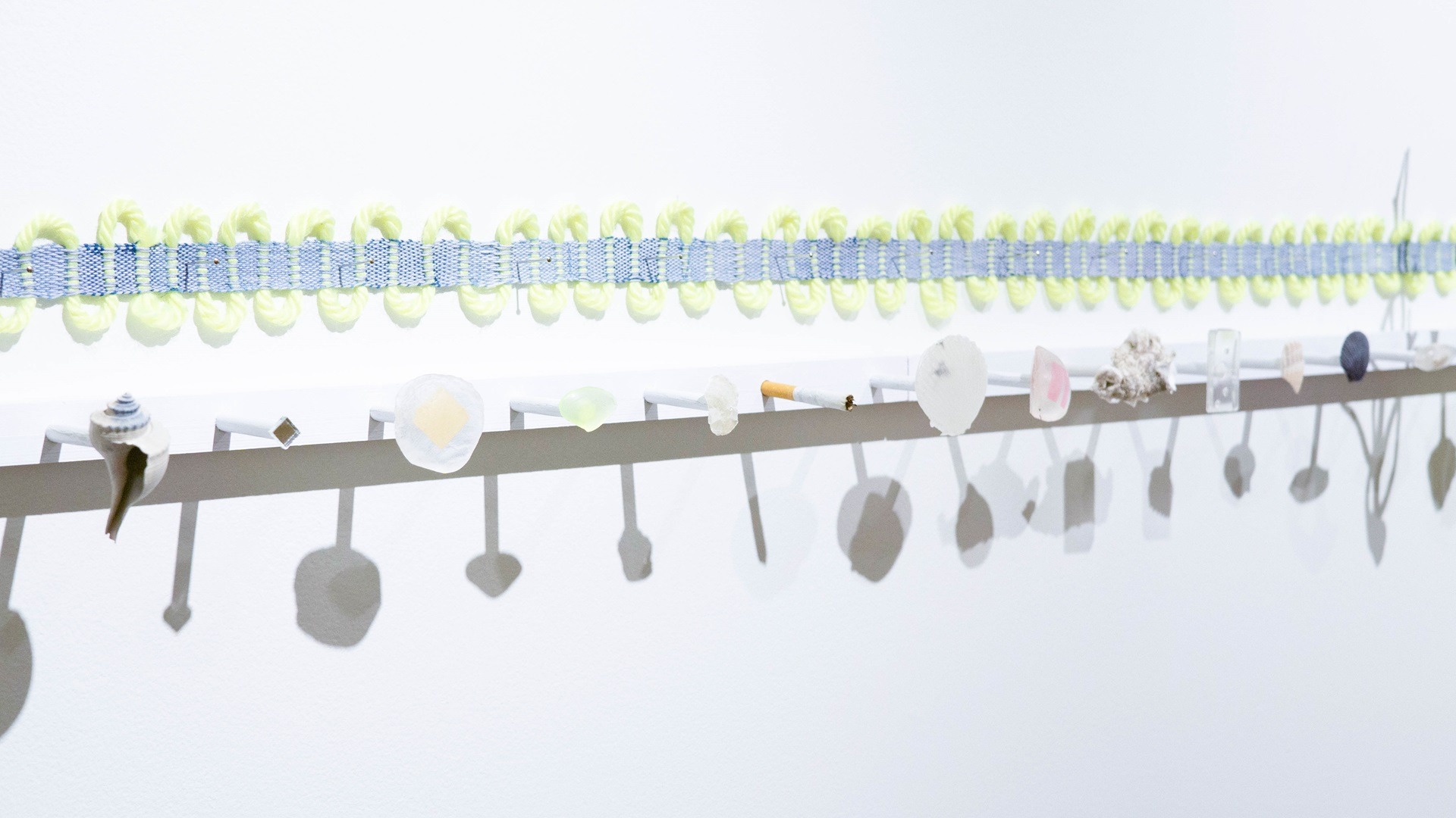 Amanda Britton, A Sea of Sinister Dots (detail), 2023. 274cm x 3cm (9' x 1"). Assemblage. Cotton, wool, shells, resin, coral, cigarette.