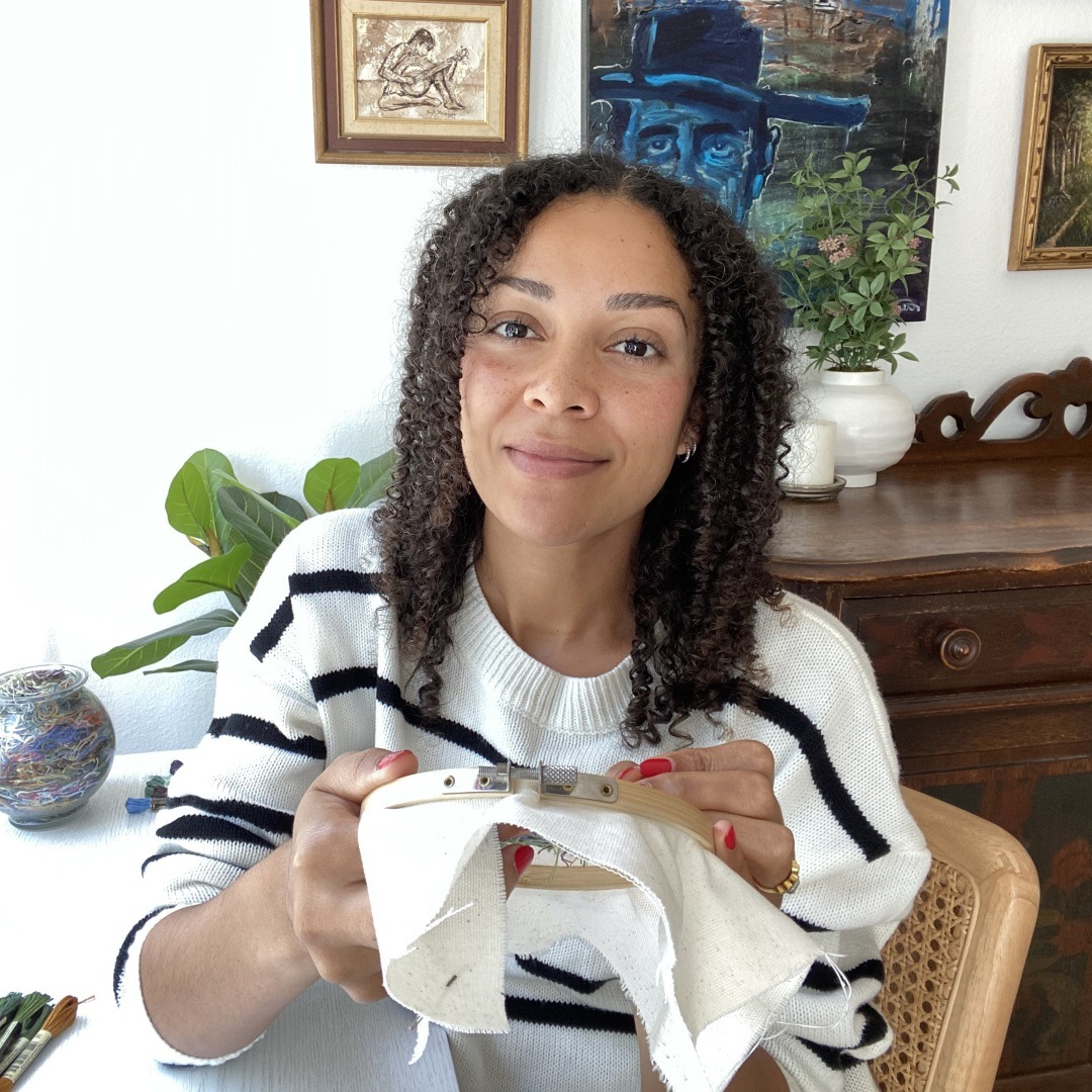 Cassandra Dias making progress on an embroidery in her workspace at home.