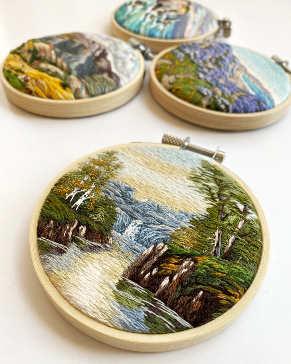Cassandra Dias, Almon Waterfall (in foreground), 2022. 9cm (3.5"). Thread painting. Cotton embroidery thread, canvas, bamboo hoop.