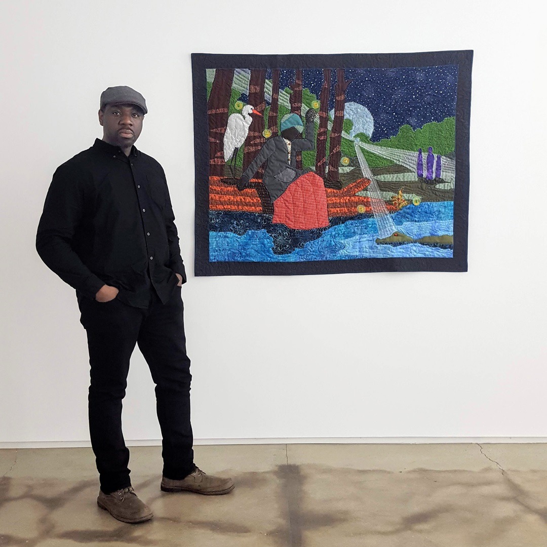 Stephen Towns standing next to his And I Shall Smite Thee quilt from the Harriet Tubman collection.
