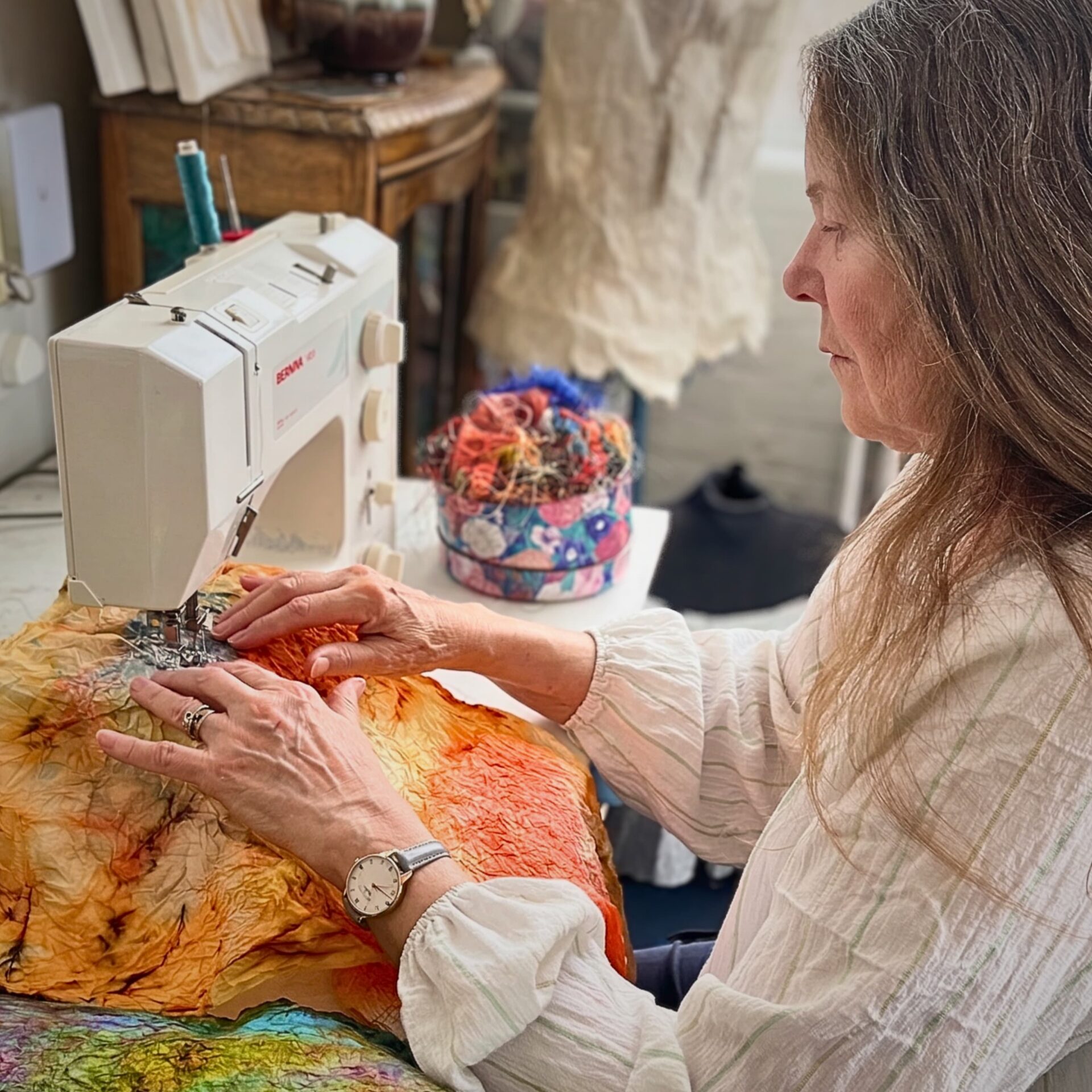 Anita Bell sewing colourful fabric artwork.