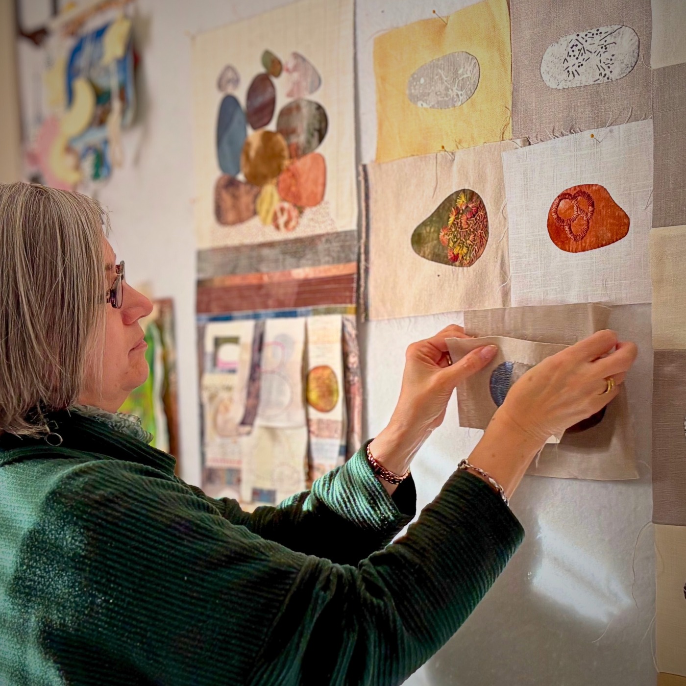 Artist arranging fabric swatches on wall.