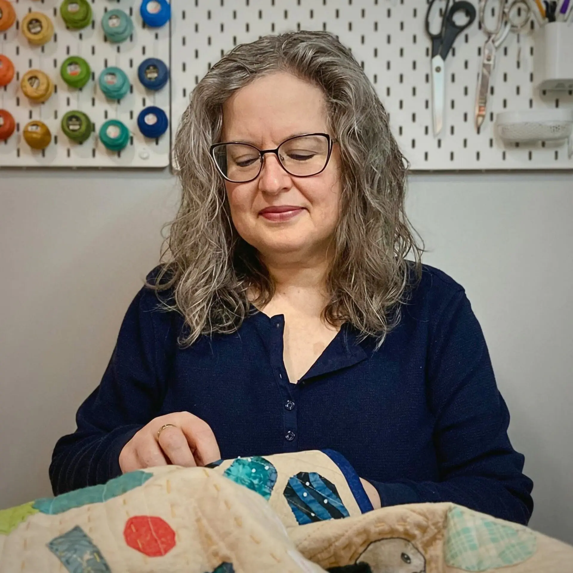 Woman sewing a quilt, focused expression.