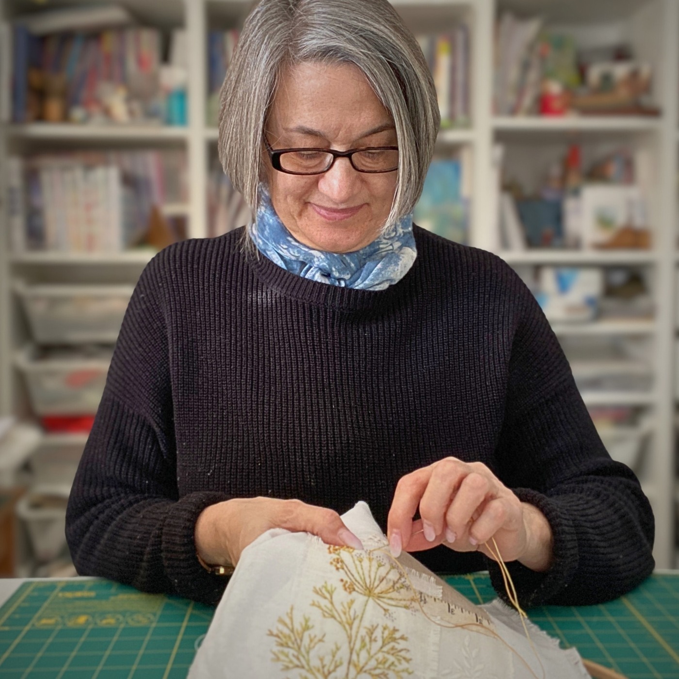 Ana Buzzalino embroidering on fabric in her studio.