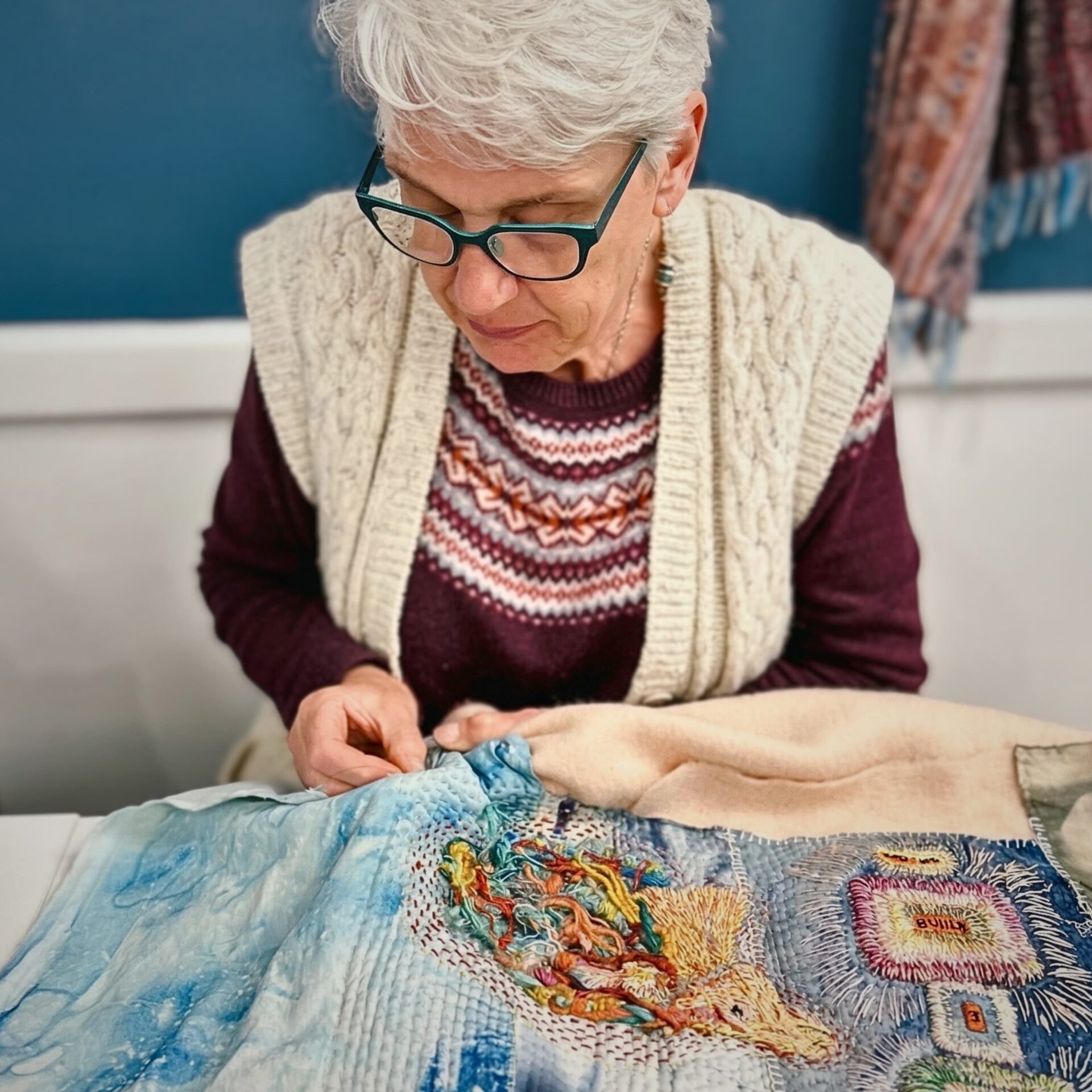 Lydia Needle embroidering intricate textile artwork.