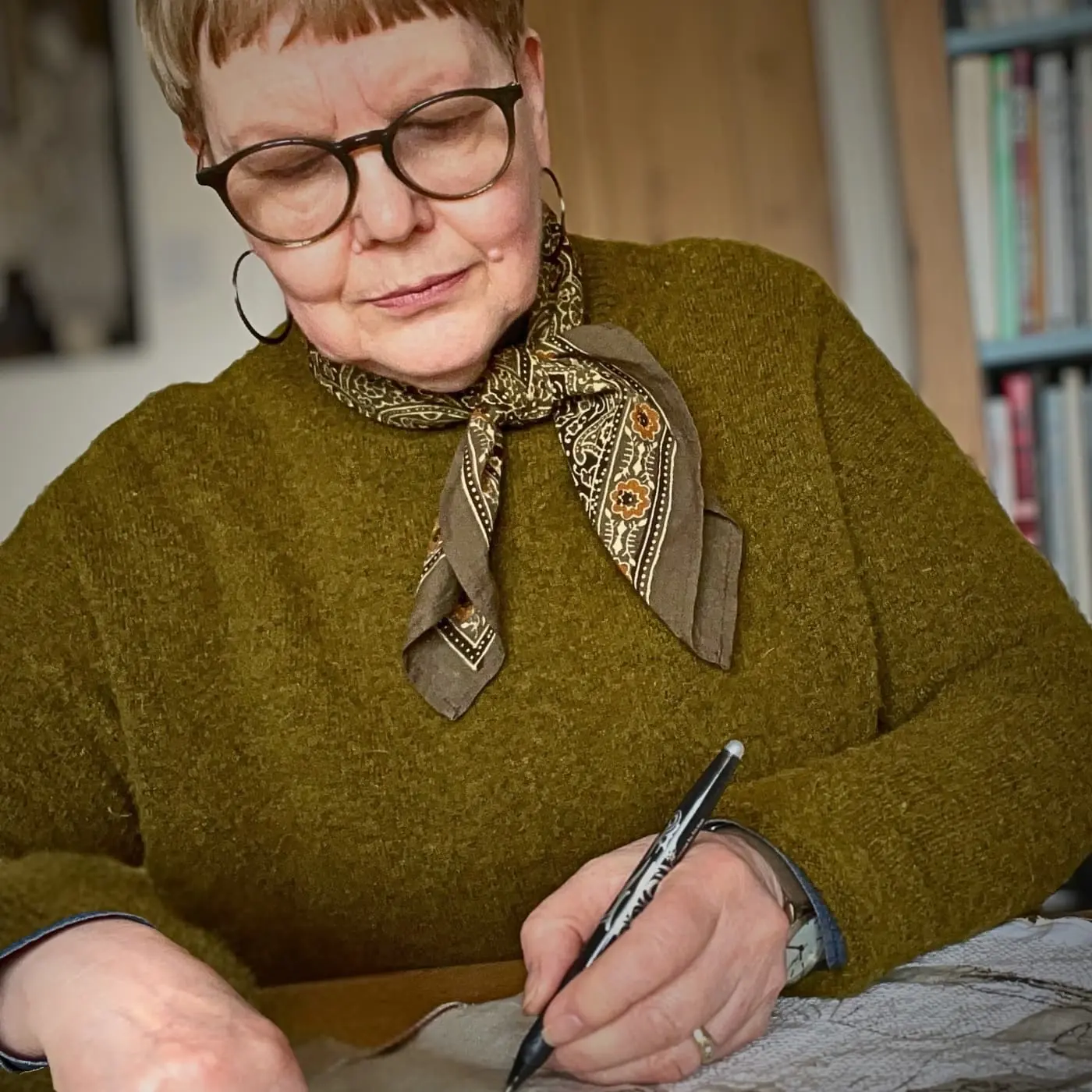 Textile artist Sue Stone drawing on paper with pen.