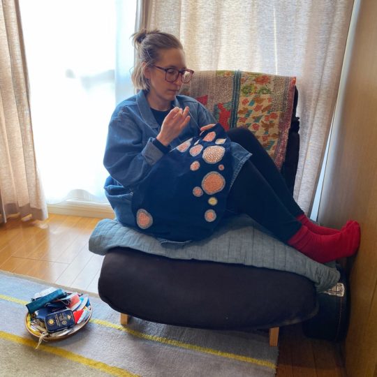 Lindsey Gradolph working in her Tokyo apartment AKA the studio, in her small chair covered in antique quilts. Photography: Ryan Fowler