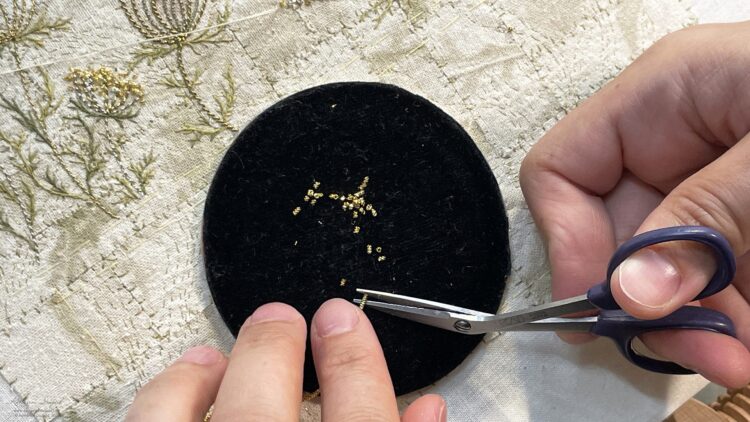 Katherine Diuguid, chopping gilt chips for an artwork, 2023. Eco printing, silk and metal hand embroidery. Eco printed silks, silk and metal threads. KAI bent scissors.