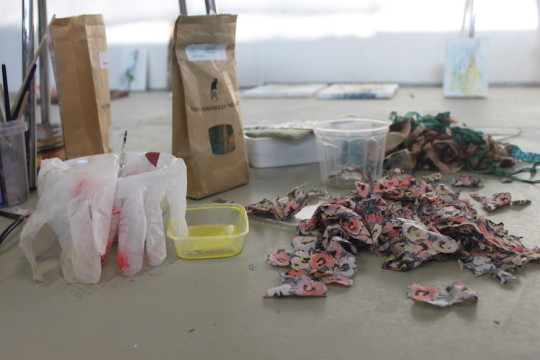 Small pieces of textiles, bags with pigments, homemade paint, bowls, brushes and latex gloves
