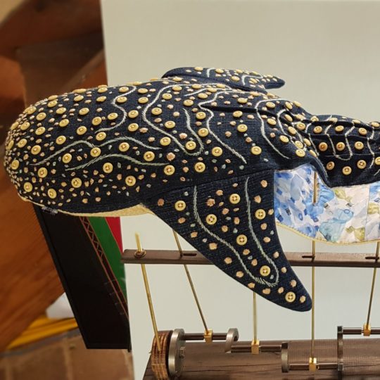 Susie Vickery, The Curious Five Go Surfing (detail: Whale Shark), 2021. 75cm x 70cm (29½" x 27½"). Embroidery, toymaking, automaton making. Fabric, brass, buttons, wood.