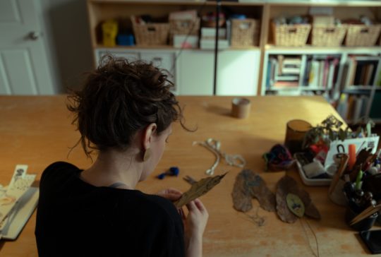 Hillary Waters Fayle stitching a leaf in her studio.