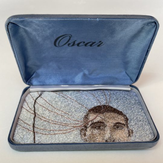 Sharon Peoples, Portrait of Oscar, 2022. Boxed embroidery: 9.5cm x 15cm x 3cm (4" x 6" x 1"). Random cross stitch hand embroidery. Cotton threads, linen fabric, mixed media.