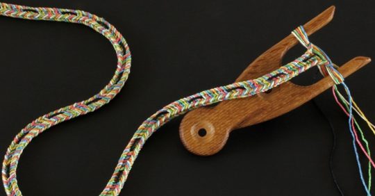 Marilyn Rathbone: 100 Metres Dash in progress (Detail), 2011-12, hand-dyed Como silk, wooden reel, black card / Inkle weaving