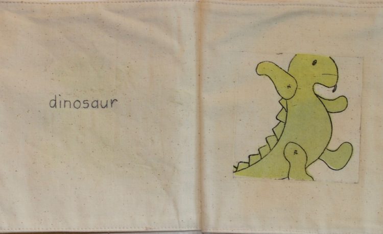 Andrea Cryer: etching - photograph of pages from the etched soft fabric book, showing dinosaur toy and handstitching