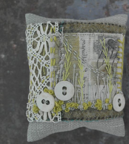 Anne Brooke: Pin cushion (2020) Printed postcard fragment, Yorkshire tweed, vintage lace, linen, button. Hand and machine stitched.