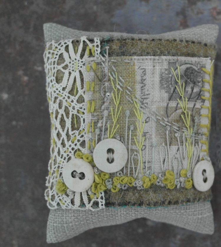 Anne Brooke: Pin cushion (2020) Printed postcard fragment, Yorkshire tweed, vintage lace, linen, button. Hand and machine stitched.
