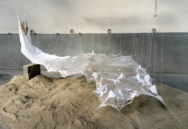 TRANSVERSUS /Performance 2020. Work in progress since 2017 Size of piece- variable dimensions : 400 x 500 x 250 cm Material and techniques : Cotton thread, wood, sand, oars, concrete, handmade lace, oil painting, hand stitching. Installation work by Sónia Aniceto Performance by Maria João Flôxo Poème : Aline Yasmin Sound interventions: Alex Cepile, voice Fanny Photos: Erwin Boosten, Monica Musoni