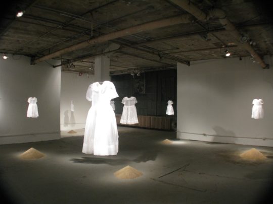 Brooks Harris Stevens: mis-tak-en, 2011, installation in variable sizes, Silk organza 3T toddler dresses embroidered with silk and cotton thread and beads and sand.