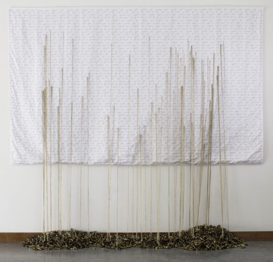 Brooks Harris Stevens: Mending Gold: When Will It Be Enough, 2017-present, 110"w X 6'h X 12"d, Custom designed fabric and stitched whole cloth quilt with gold thread and brass bullet casings.