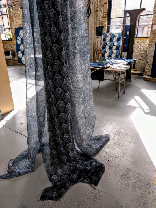 Sarah Desmarais: Printed silk organza lengths hung as part of an installation at Craft Central, London, 2019, Individual lengths 3m long and 112cm wide, Silk organza, printed with a rice paste resist using hand cut stencils, and dyed with fibre reactive dyes
