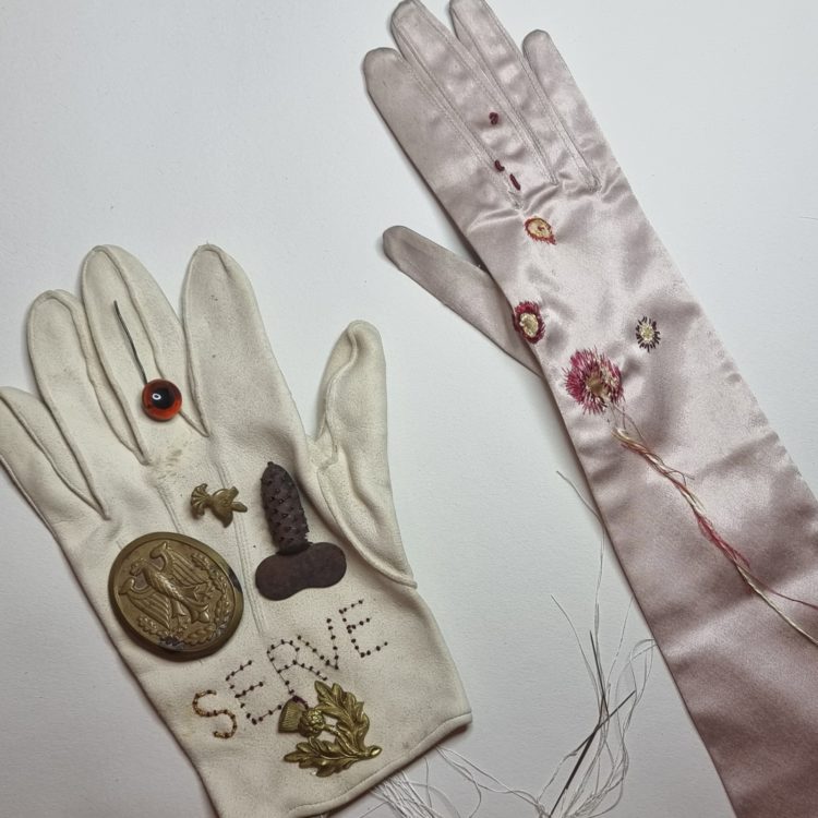 Andrea Mindel, Astride The African Continent Like A Colossus (left glove) and Wound (right glove), 2017 and 2021. 30m x 30cm (12" x 12"). Hand Embroidery and found objects on leather ceremonial glove: Silk on silk glove.