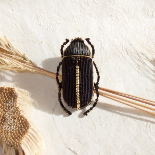 Claire de Waard, Black Goldwork Beetle Brooch, 2022. 5cm x 3cm (2" x 1¼"). Stumpwork, beading, goldwork, straw embroidery. Dyed straw, goldwork threads, wool padding, seed beads.