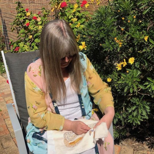 Joy Denise Scott stitching in her friend’s garden.