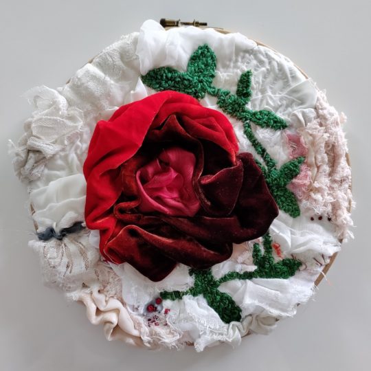 Jane Axell, Soft, red rose, 2022. 30cm x 30cm (12” x 12”). Hand Stitch. Cotton backing fabric, variety of fabrics, variety of threads, hoop.