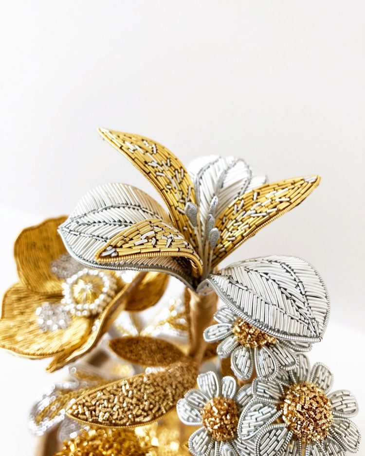 Hannah Mansfield, Summer Goldwork Flower Sculpture (detail), 2019. 40cm x 20cm (15 ¾” x 7 ¾”) including glass dome. Goldwork. Gold and silver goldwork wires, silk organza, metallic thread, metal beads, metallic leaf, silk ribbon, wire, tissue paper and clay.