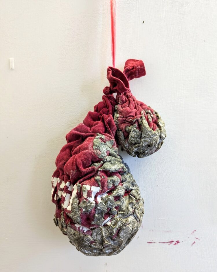 Nerissa Cargill Thompson, The Party's Over: Remains of the Day, 2023. 30cm x 15cm x 50cm (11¾" x 6" x 19½"). Manipulated with stitch and dipped in concrete. Old t-shirt, stuffing, concrete, plastic raffia string. 