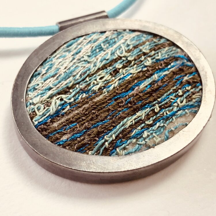 Dionne Swift, Deep Sea Textures, 2023. 8cm diameter (3"). Traditional silversmithing techniques of forming and soldering, free machine embroidery. Hallmarked silver, cotton, rayon and metallic threads, elastic cord.