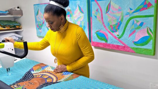 Clara Nartey free motion embroidering on Amandla using a long arm quilting machine in her studio.