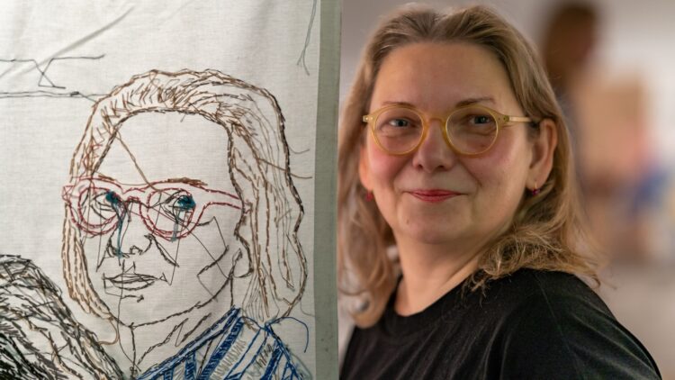 Eva Cieniak and her self portrait from Embroidered, an exhibition at BWA Gallery in Kielce, Poland. Photo: Katarzyna Samczynska.