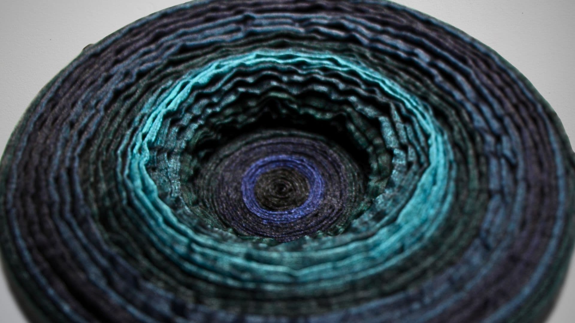 Close up of a whirlpool like textured artwork made from various recycled materials.