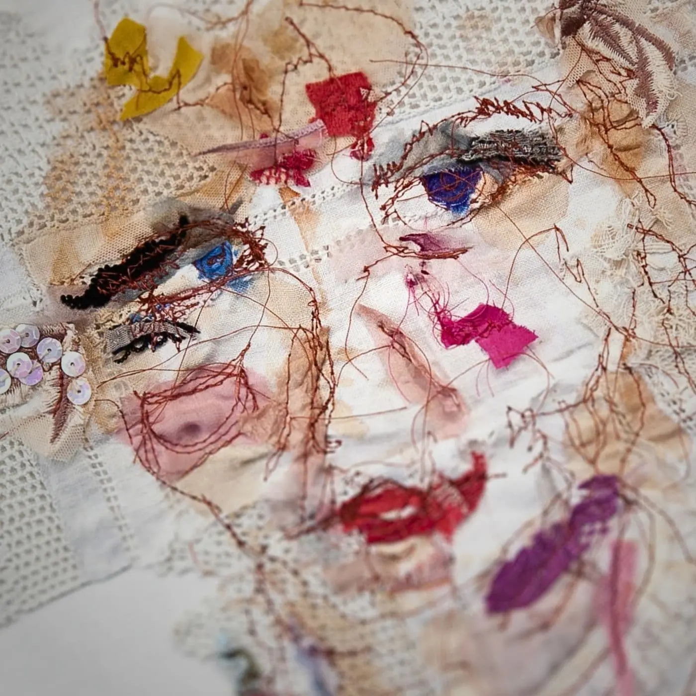 A close up of a face using mixed media materials with mixed textiles
