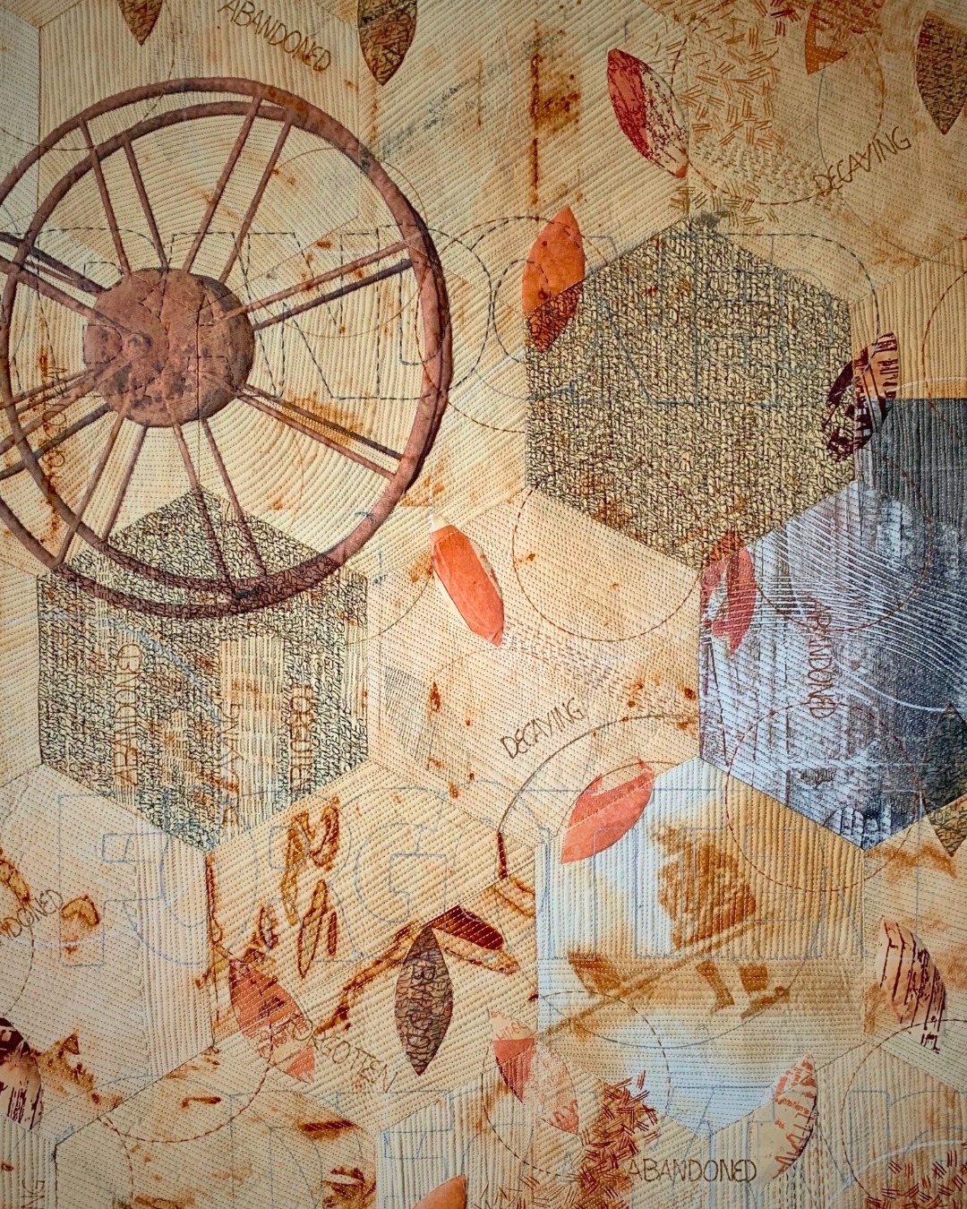 Abstract textile collage with wheel and leaves.