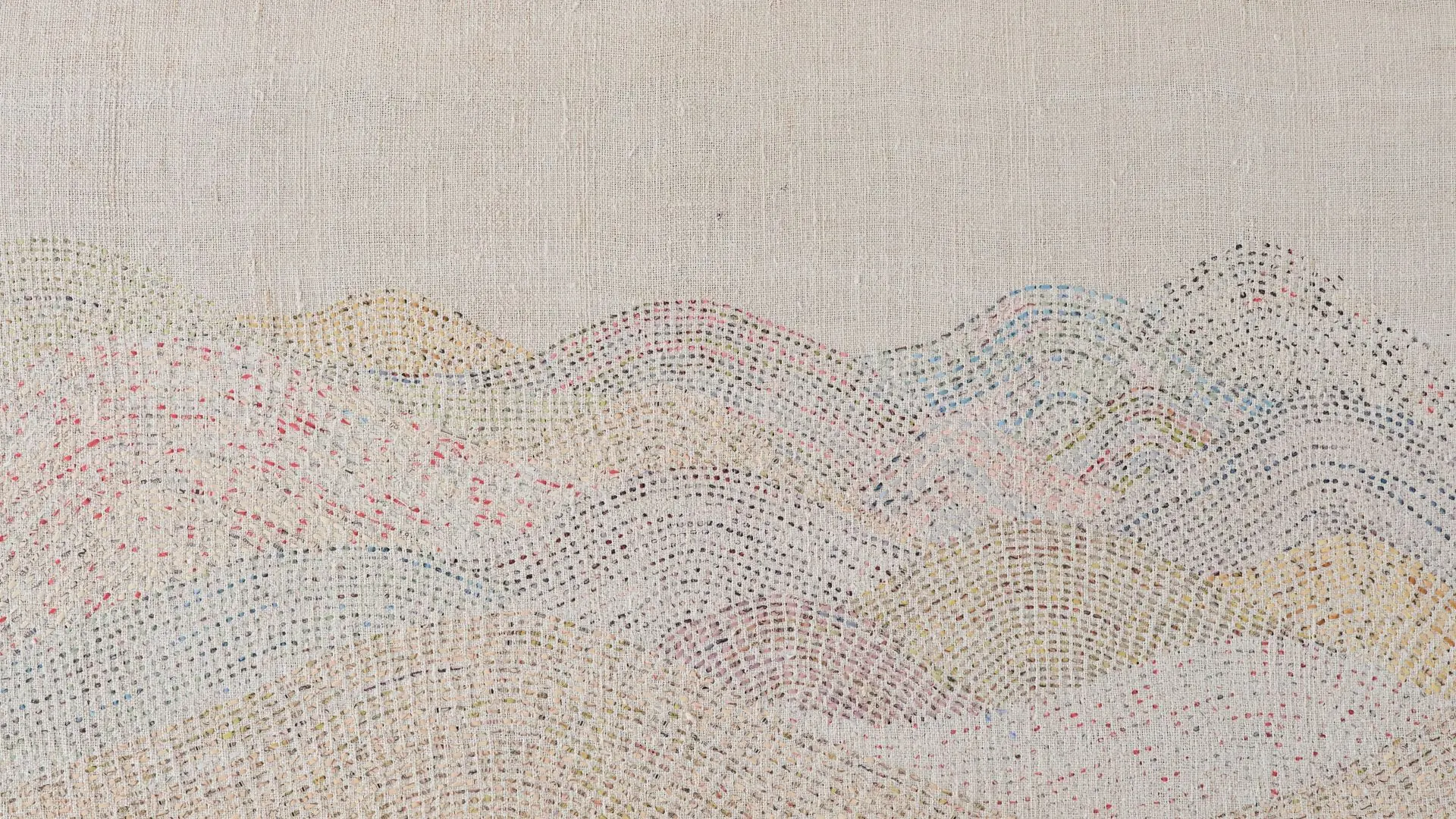 A stitched artwork representing a delicate mountain range on linen