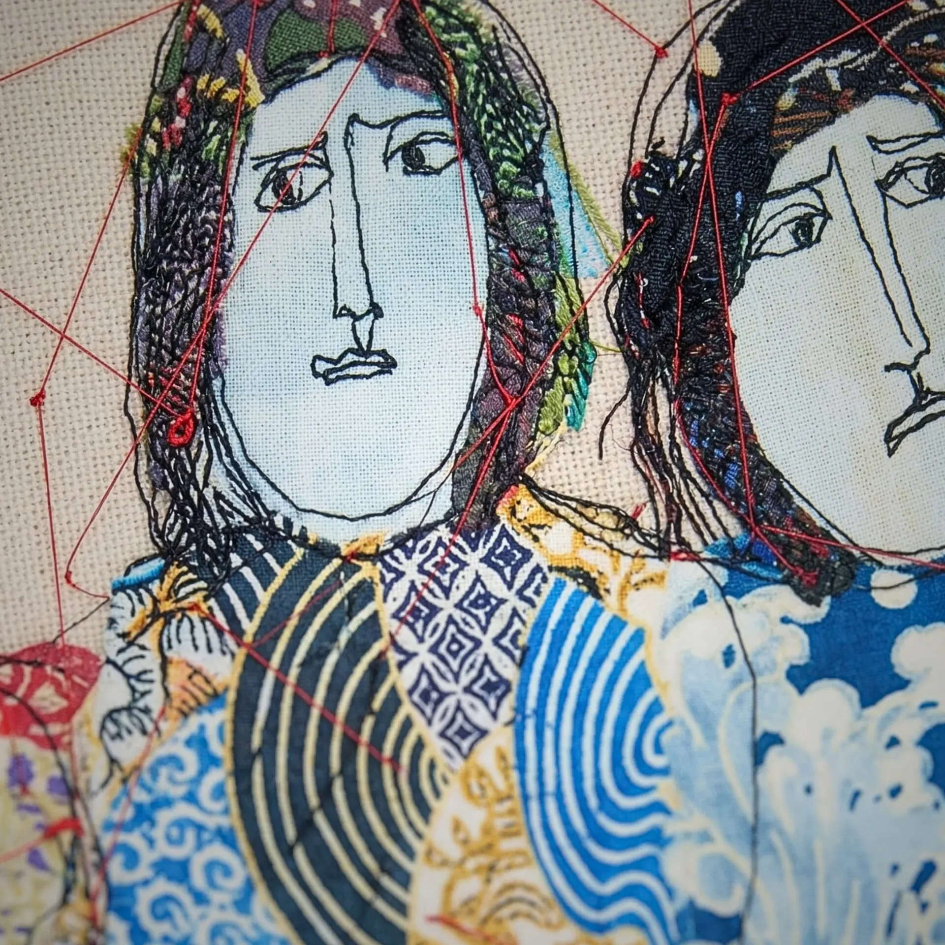 Two embroidered faces with colourful patterns.
