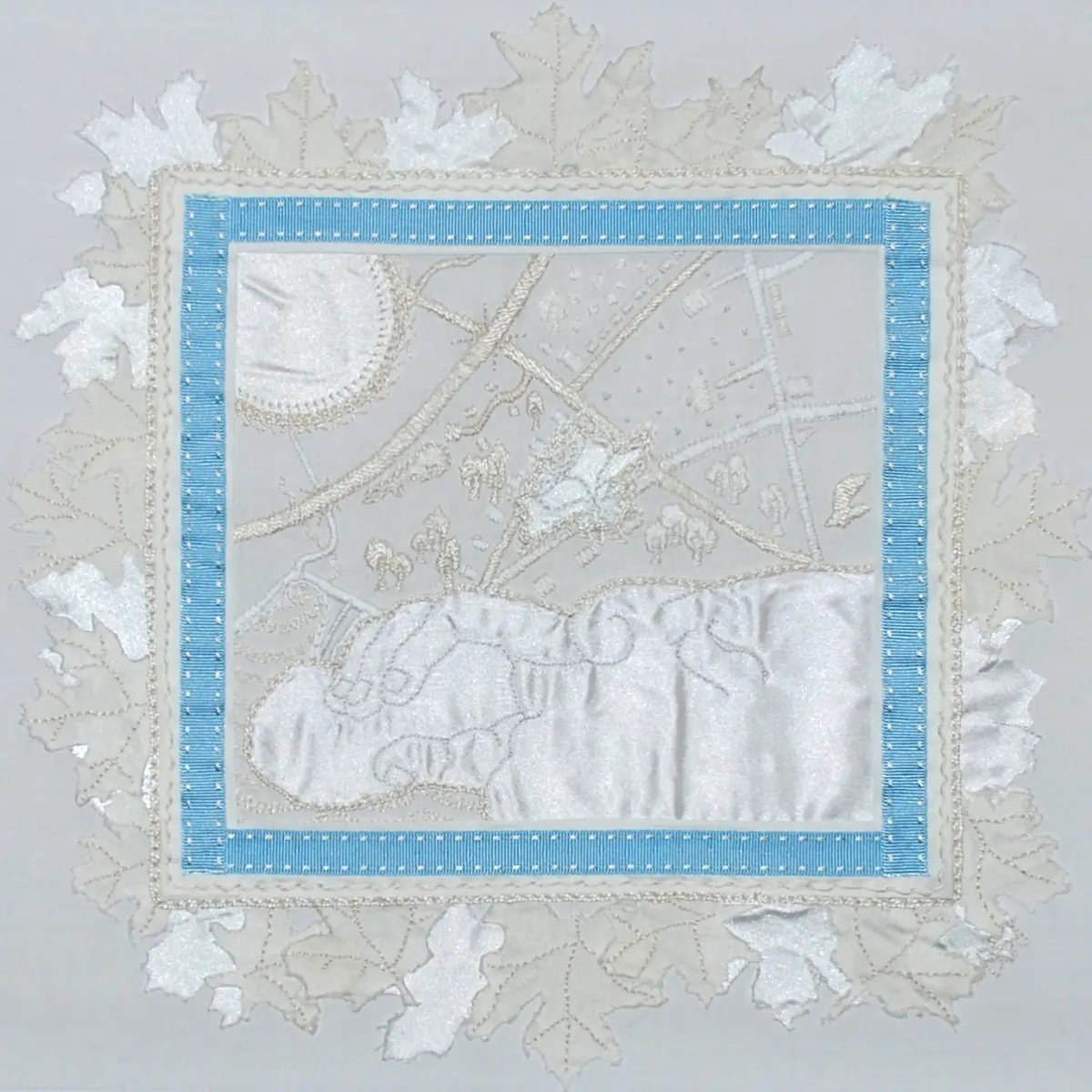 A white and blue textile art piece with silk and embroidery