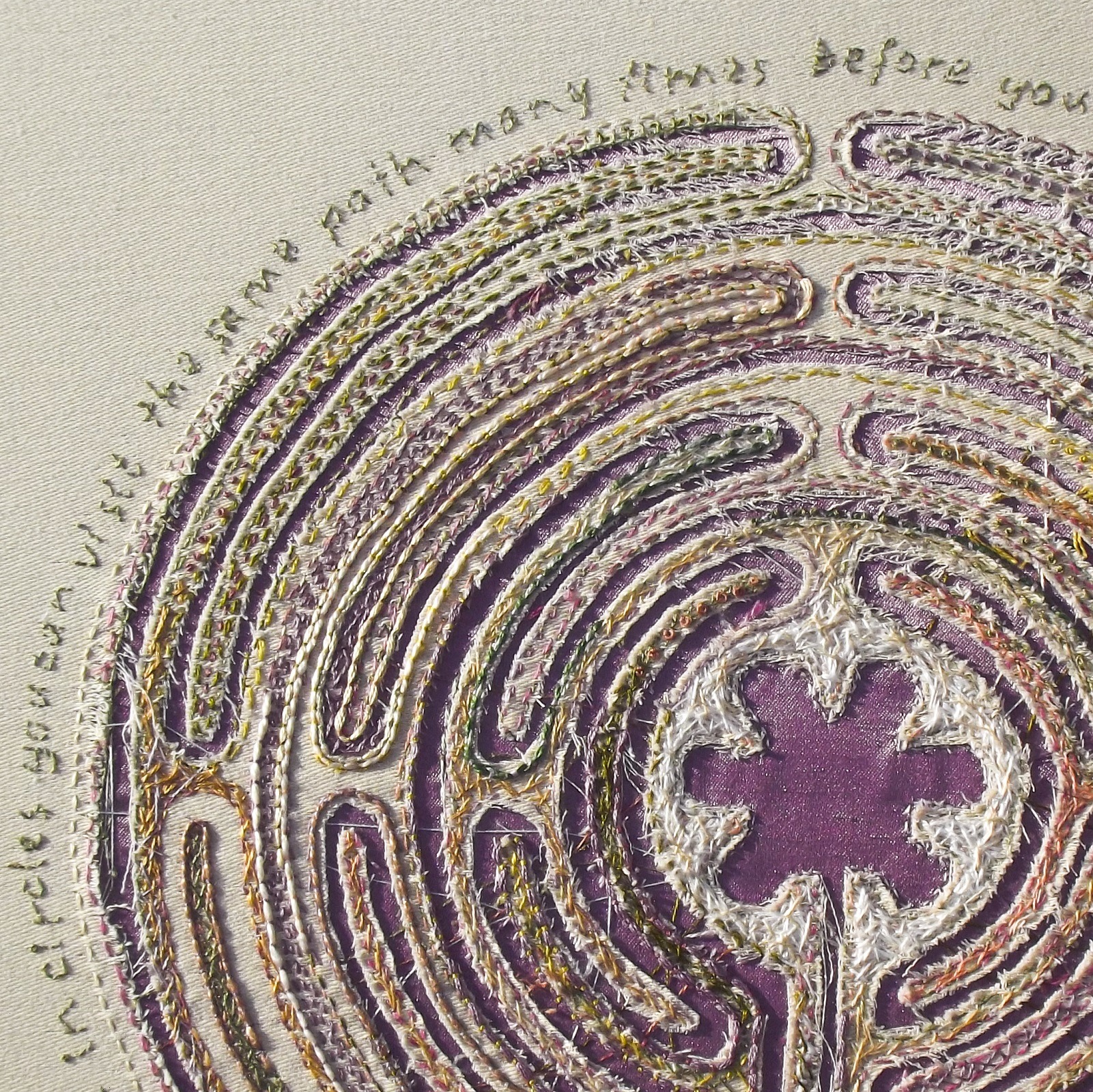 A close-up of stitched artwork circular design and embroidered text around
