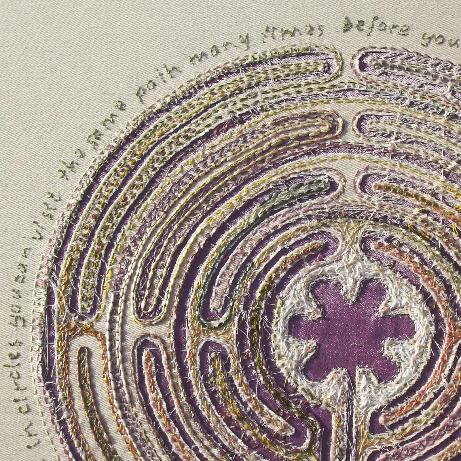A close-up of stitched artwork circular design and embroidered text around