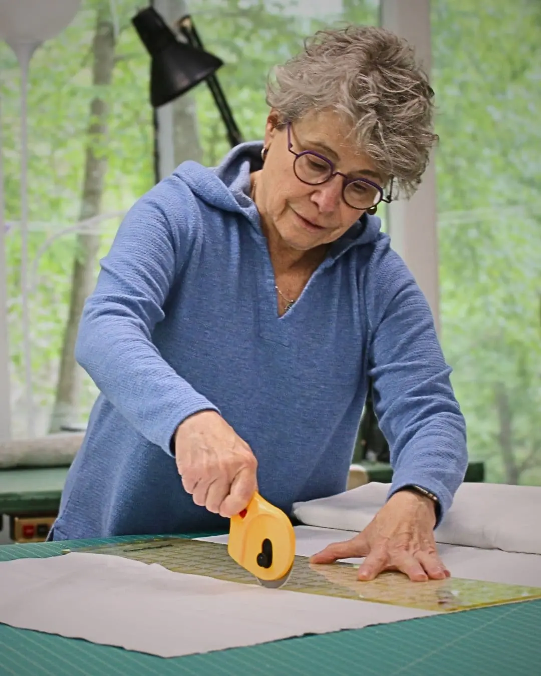 Textile Artist Cheryl Rezendes cutting fabric in her studio