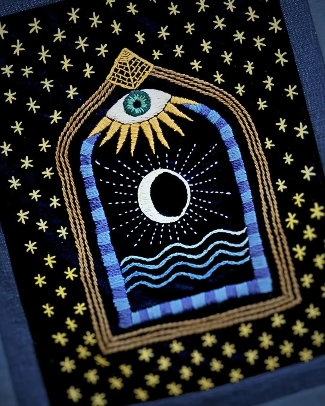 a close-up of a embroidered picture featuring a mythical doorway with an eye above it