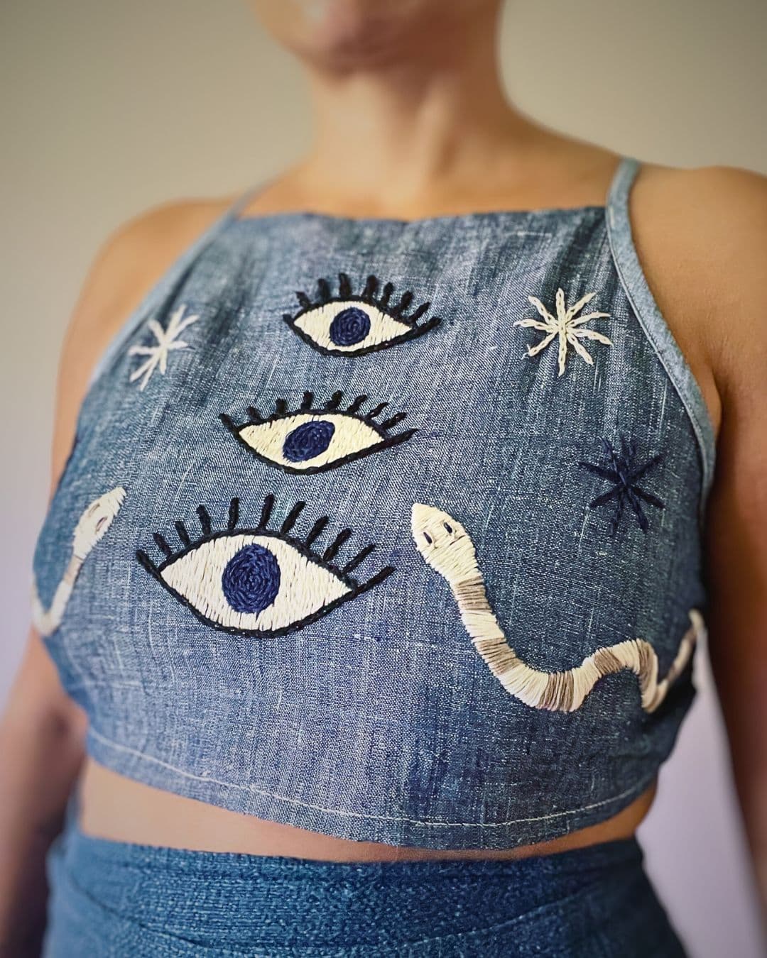 Denim halter neck top with 3 eyes and serpents embroidered on it