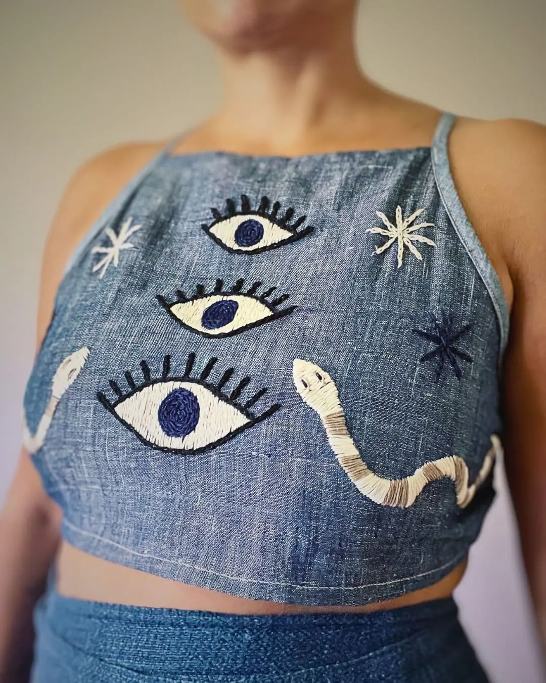 Denim halter neck top with 3 eyes and serpents embroidered on it