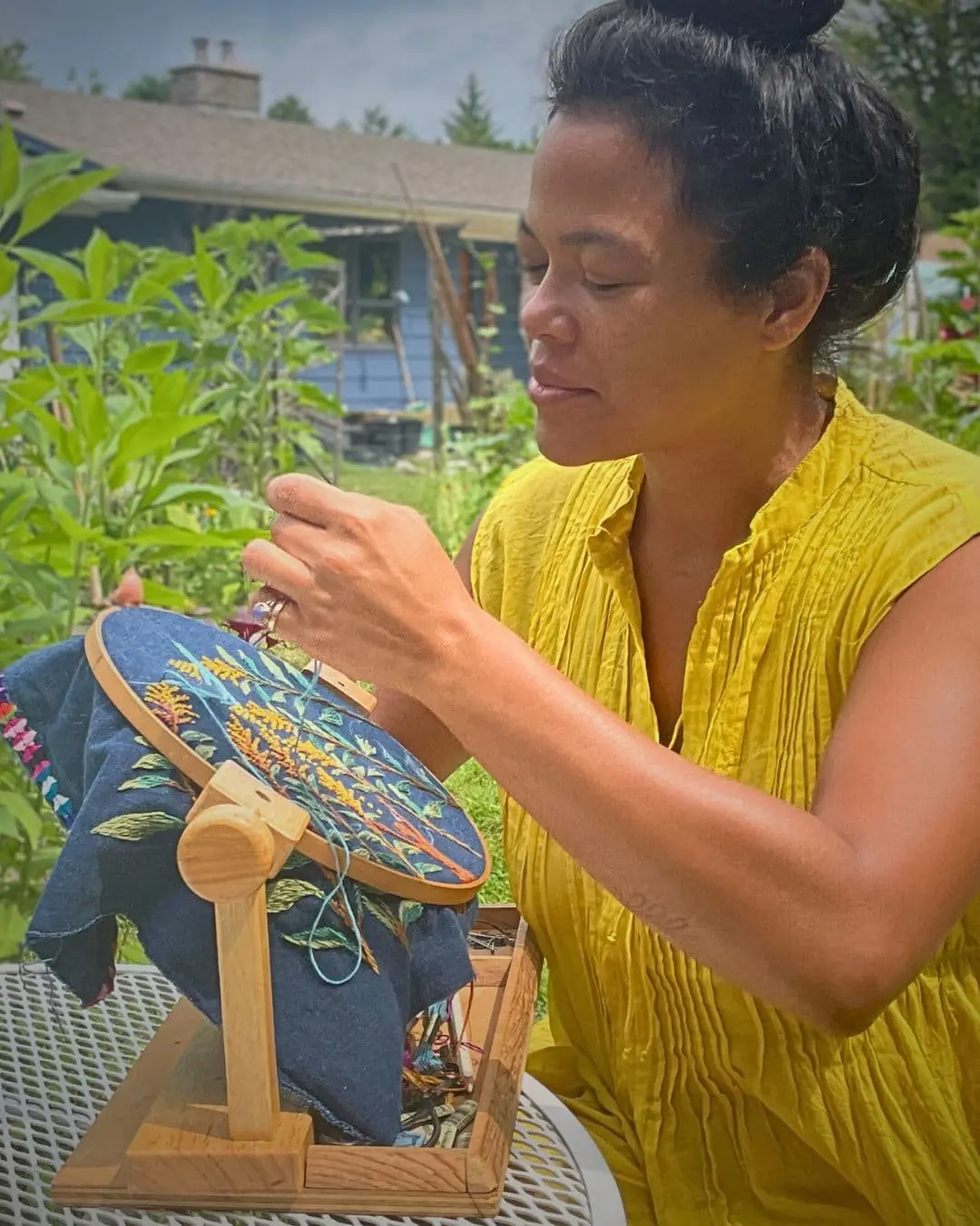 Textile Artist Christi Johnson stitching outside her home.