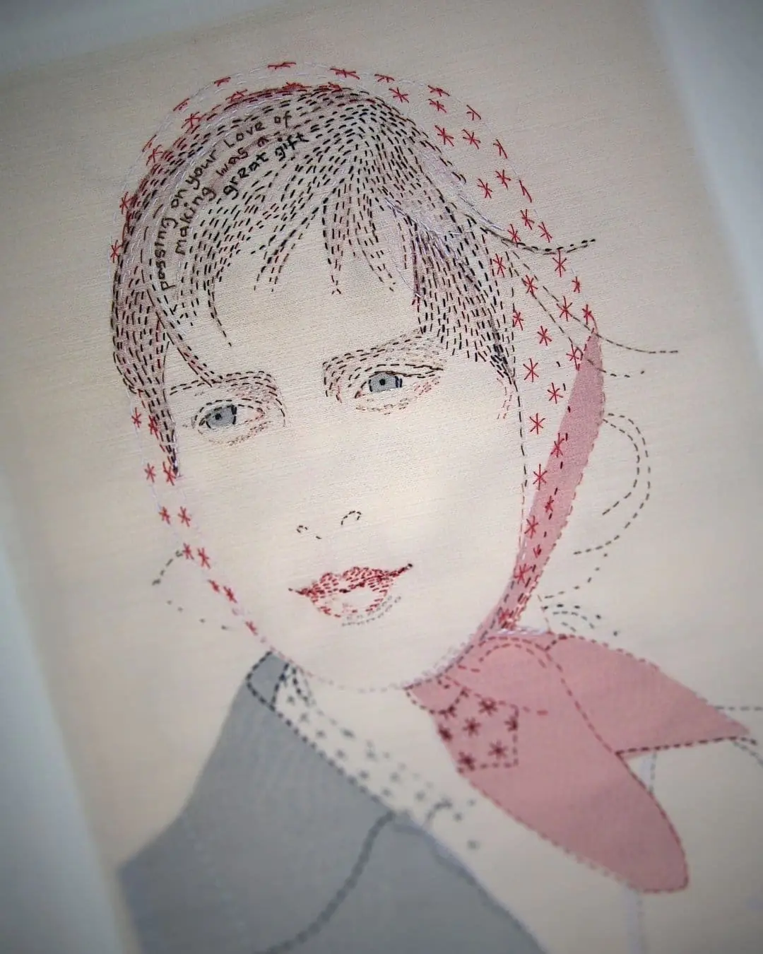 A Textile artwork featuring an embroidered portrait of a girl.