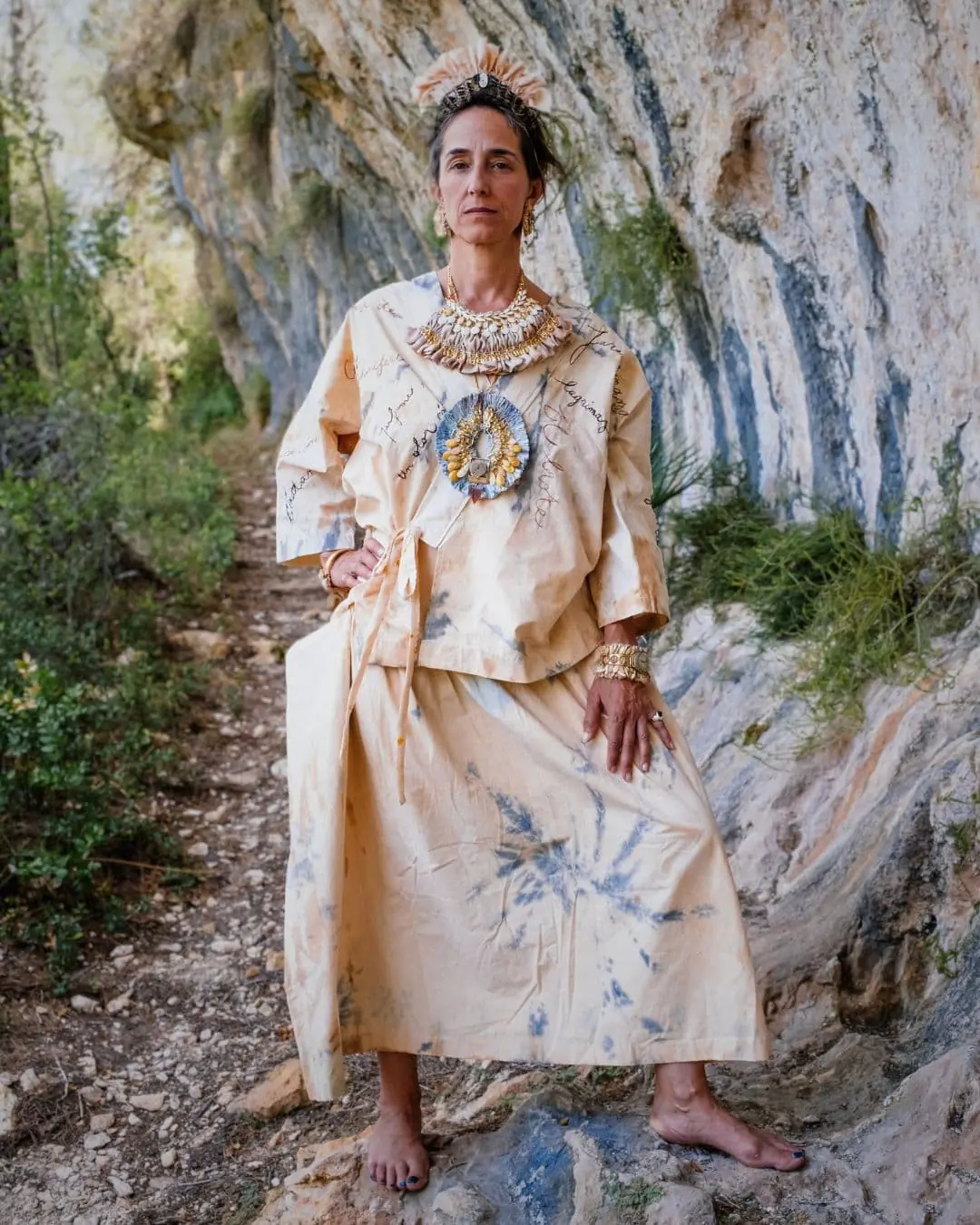 A woman standing on a rock in an embroidered dress