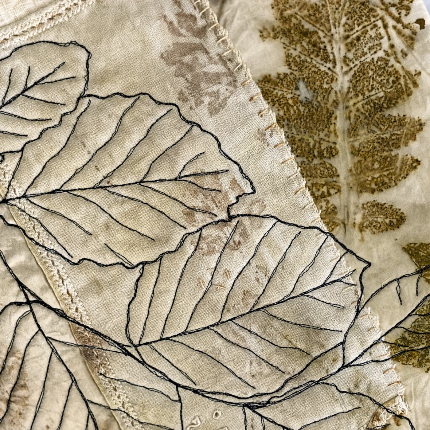 Textile art featuring embroidered leaves.