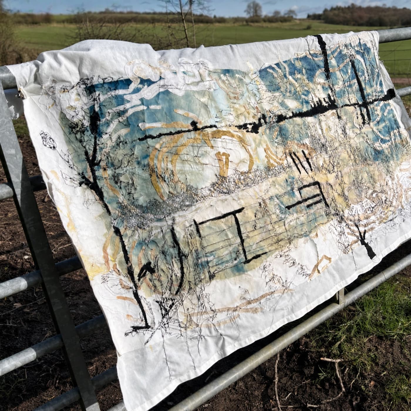 Artistic textile hanging on fence.